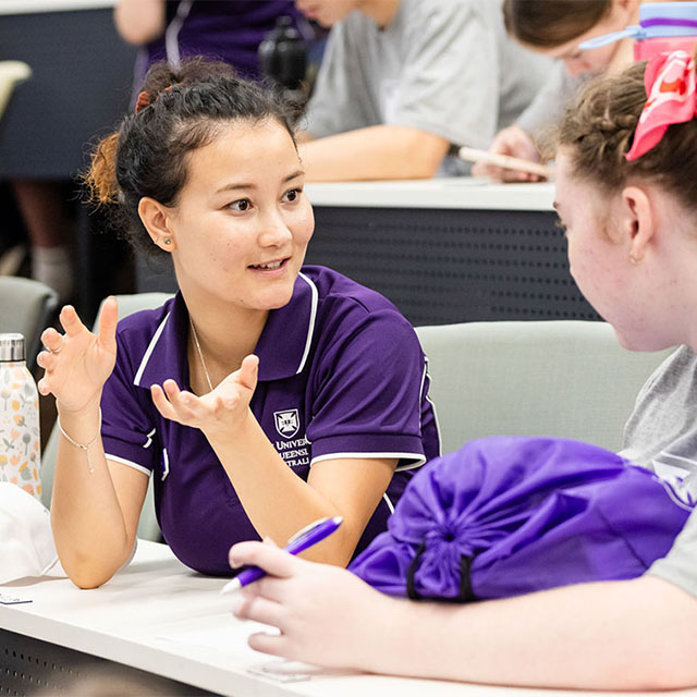 Mentor explains something to a student they are sitting with.