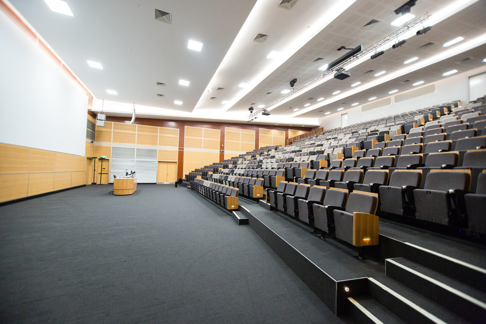 Large room with tiered rows of seating facing a lectern and screen