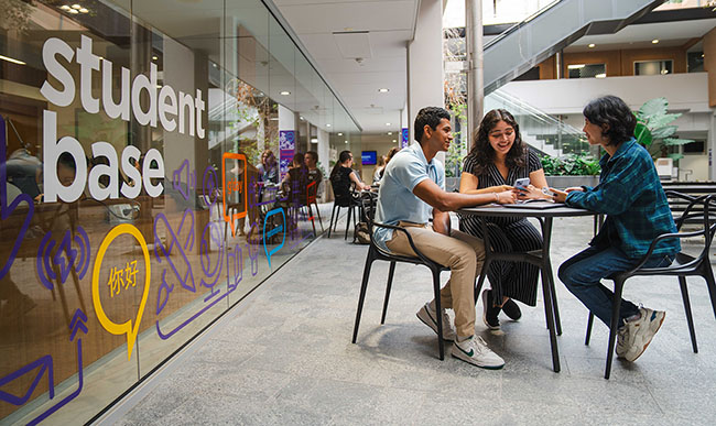Students sitting at a table chatting at BEL Student Base.